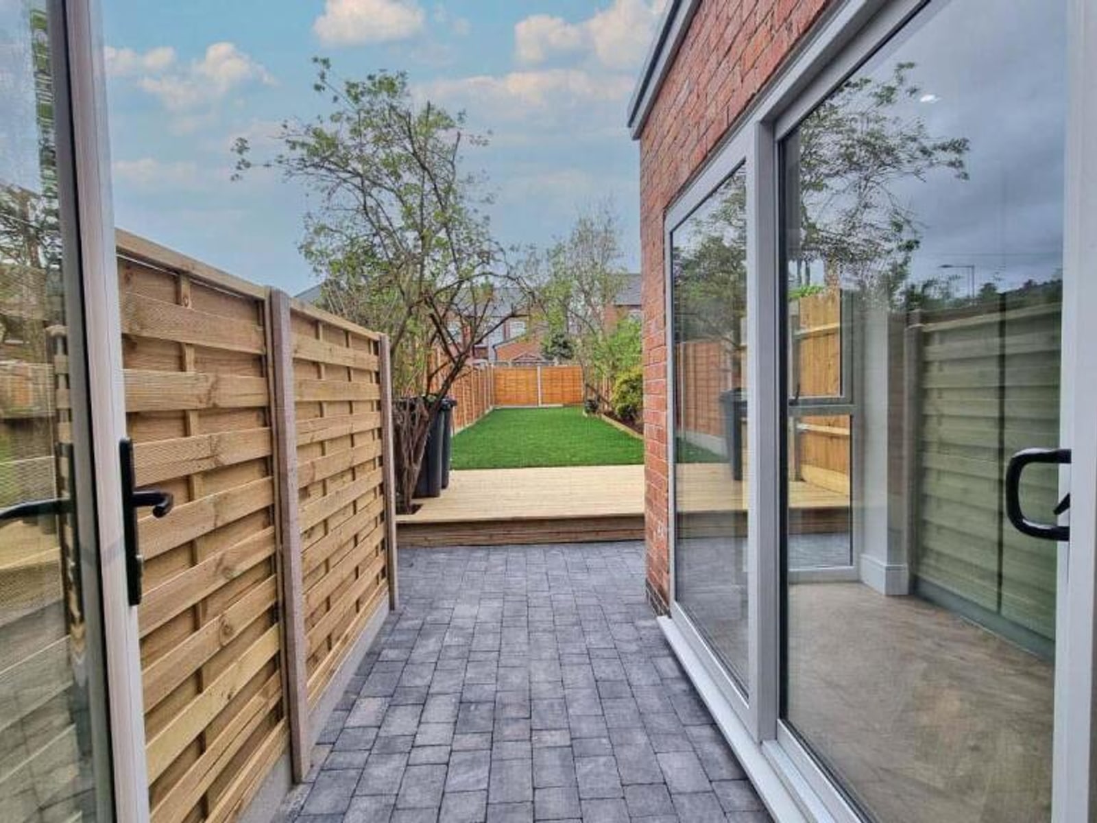 Newly laid block-paved patio with sliding doors out to a landscaped garden