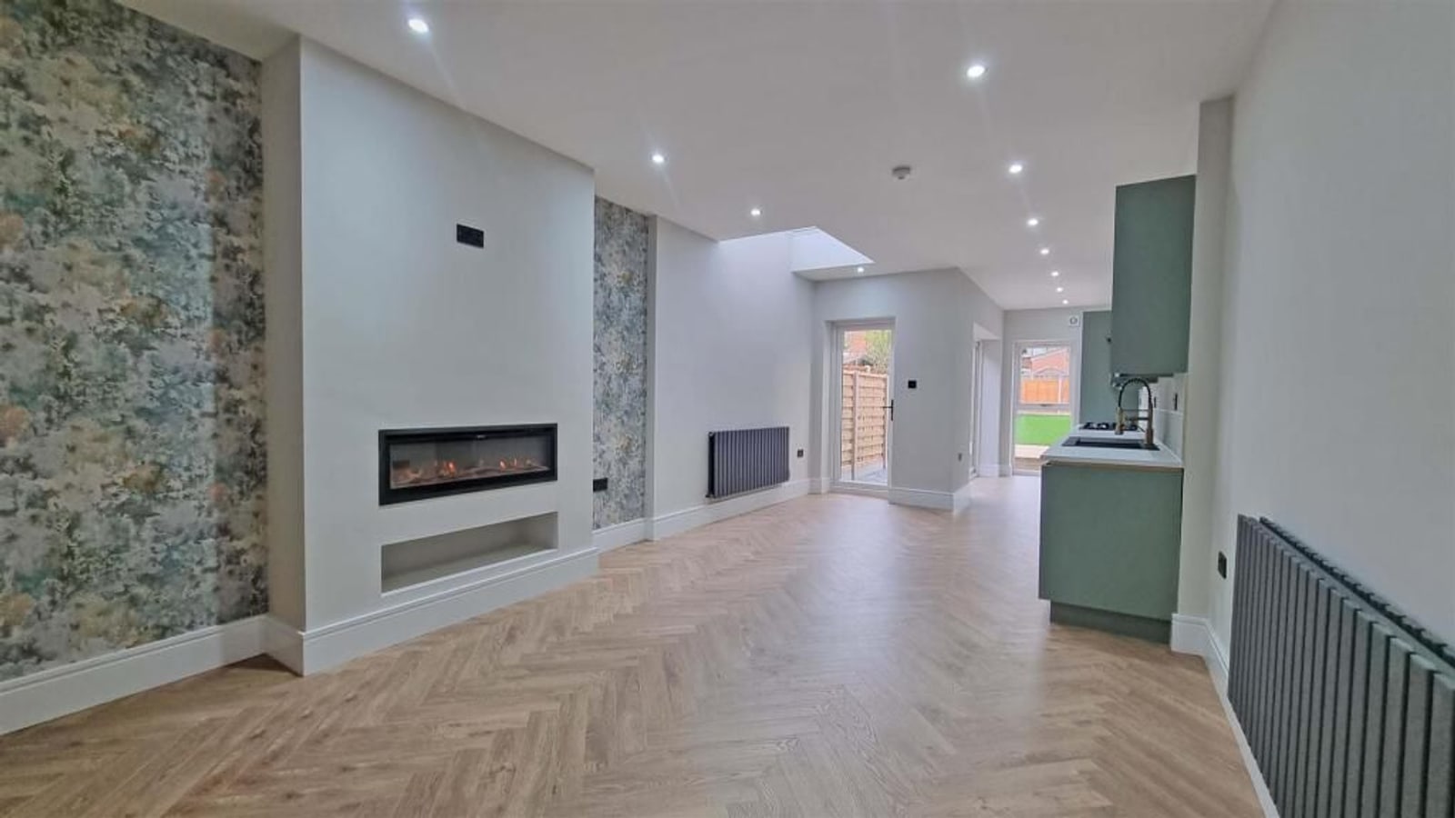 Open-plan kitchen and lounge with feature fireplace, herringbone floor and bespoke joinery, finished by Sunnyside